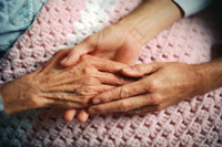 Elderly woman holding hands with loved one